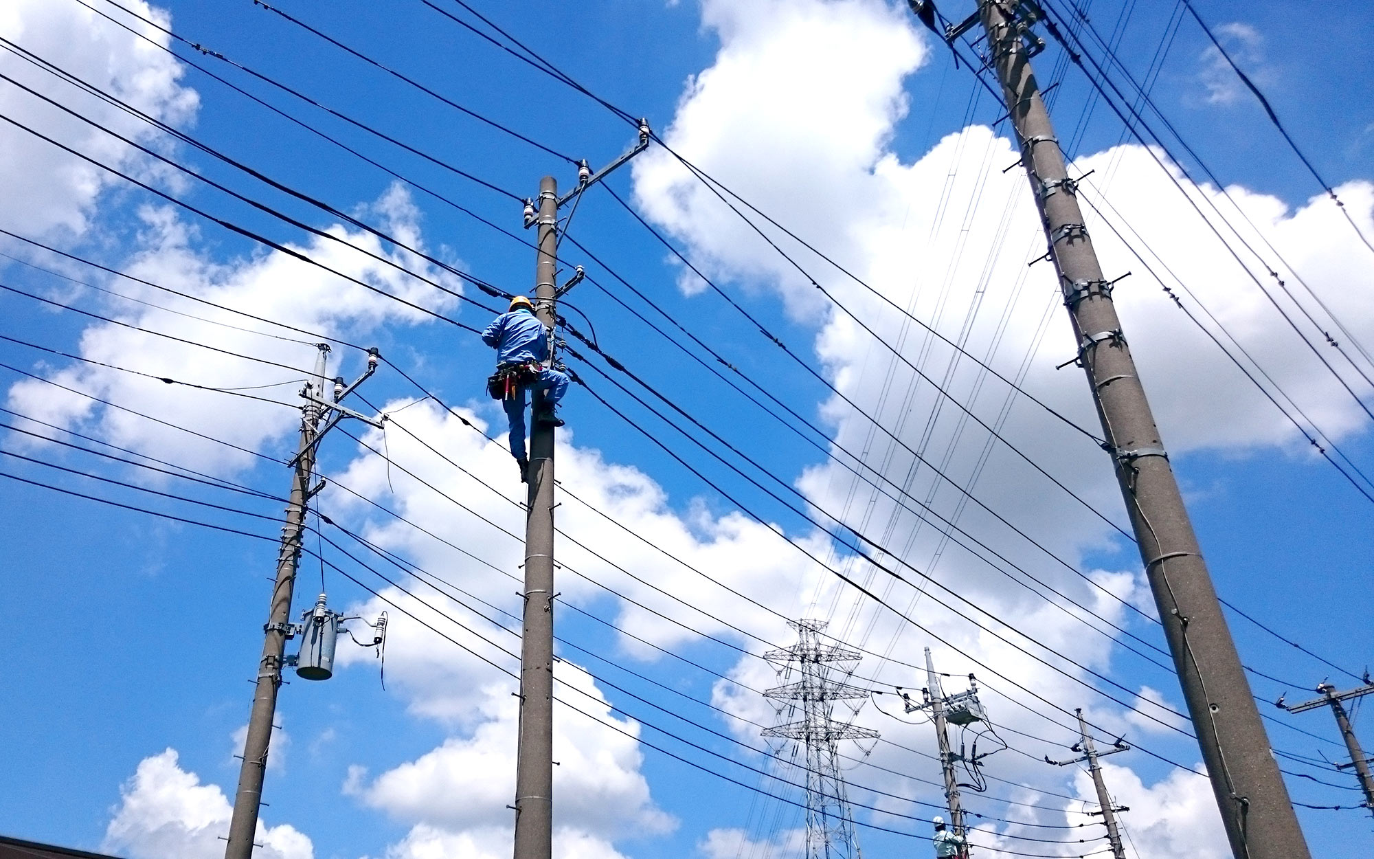 栄電業株式会社の業務イメージ 電柱の上で電気工事作業をする従業員